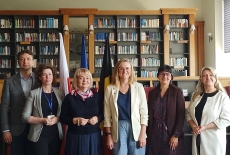 Zdjęcie grupowe. Uczestnicy spotkania stoją na tle regału z ksiązkami.