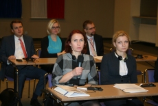 Uczestnicy seminarium siedzą w ławkach. Jedna osoba zabiera głos przez mikrofon.