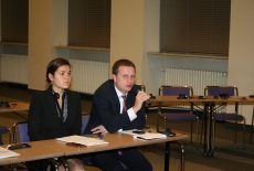 Uczestnicy seminarium siedzą w ławkach. Jedna osoba zabiera głos przez mikrofon.