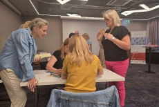 Uczestnicy siedzą przy stole i pracują.