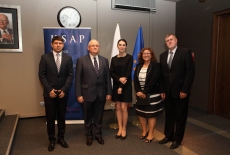 Goście z zagranicy stoją z Dyrektorem Janem Pastwą w Auli KSAP na tle roll up KSAP i flag UE i Polski