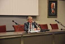 Pan Paweł Soloch siedzi przy stole prezydialnym i mówi do mikrofonu