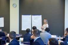 uczestniczka stoi przy ścianie na której rozwieszone są wykresy i notatki