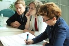 Uczestnicy warsztatu siedzą w ławce i notują