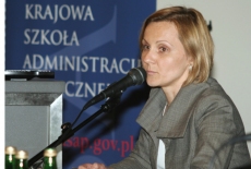 Pani mówi do mikrofonu na tle baneru KSAP