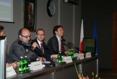 Za stołem prezydialnym siedzą prowadzący konferencję