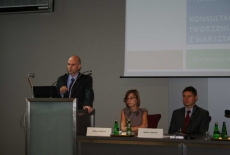 Pan stoi na mównicy i przemawia siedzą prowadzący  konferecję