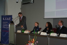 Pan stoi na mównicy i przemawia siedzą prowadzący  konferecję