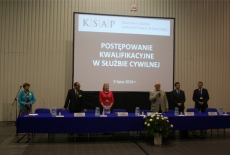 Rozpoczęcie Postępowania Kwalifikacyjnego w Służbie Cywilnej, członkowie komisji stojąc pod rzutnikiem witają kandydatów. Do mikrofonu przemawia dyrektor KSAP Jan Pastwa.