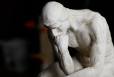 Rzeźba przestawia mężczyznę siedzącego i myślącego