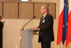 fot. Sebastian Szulfer/KSAP Pan przemawia na mównicy na tle flag Polski i UE