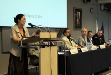 Pani stoi na mównicy i przemawia  za nim wyświetlana jest prezentacja