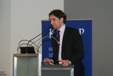 Marcin Sakowicz mówi do mikrofonu stojąc przy mównicy.