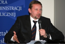 Uczestnik sesji warsztatowej mówi przez mikrofon siedząc.