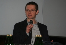 Uczestnik sesji warsztatowej mówi przez mikrofon siedząc.