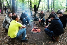Słuchacze siedzą przy ognisku.