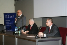 Dyrektor Jan Pastwa przemawia podczas spotkania z marszałkiem Senatu RP Bogdanem Borusewiczem przemawia stojąc. Obok niego siedzi marszałek Borusewicz i Marek Gajdziński.