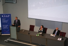  Ambasadorem Felipe Gajardo przemawia przy mównicy, a prozostali prelegenci siedzą przy stole.