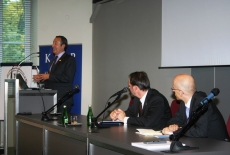  Ambasadorem Felipe Gajardo przemawia przy mównicy, a prozostali prelegenci siedzą przy stole.