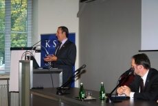  Ambasadorem Felipe Gajardo przemawia przy mównicy, a prozostali prelegenci siedzą przy stole.