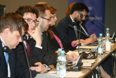 Uczestnicy siedzą przy stole zasłuchani, jedna osoba notuje.