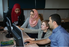 Przy komputerze prowadzący objaśnia trzem uczestnikom szkolenia