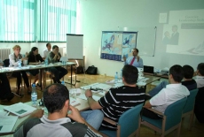 Uczestnicy szkolenia siedzą w ławkach po środku Pan prowadzący