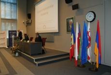 Dyrektor KSAP przemawia na mównicy, w rogu auli stoją na stojakach