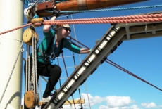 Uczestniczka rejsu szkoleniowego po Morzu Bałtyckim wspina się na elementy konstrukcyjne ożaglowania.