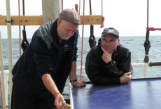 Dwóch zamyślonych uczestników rejsu. Żaglowiec jest na pełnym morzu.