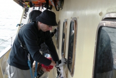 Podczas rejsu dwoje uczestników czyści okna burtowe.