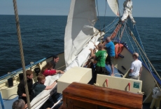 Uczestnicy rejsu zwijają  żagiel.