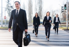 pięć osób ubranych w formalne stroje przechodzi przez przejście dla pieszych