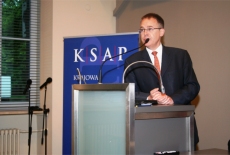 Uczestnik spotkania wygłasza mowę stojąc przy mównicy.