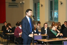 Uczestnik spotkania zadaje pytanie stojąc pośród siedzących słuchaczy.