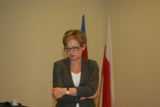 Uczestniczka wizyty studyjnej stoi zasłuchana na tle flag.