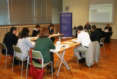 Ośiem osób siedzi przy stole ustawionym w podkowę, wszyscy słuchają wypowiadającego się z głębi sali dyrektora KSAP Jana Pastwy.