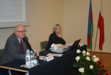 Dyrektor Jan Pastwa siedzi obok jednej z uczestniczek wizyty studyjnej. Dyrektor mówi do mikrofonu, a uczestniczka siedząca po jego lewej stronie uśmiecha się.