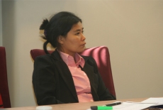 Uczestniczka spotkania siedzi przy stole zasłuchana.