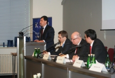 Przy mównicy przemawia Dagmir Długosz dyrektor Departamentu Służby Cywilnej w Kancelarii Prezesa Rady Ministrów. Pozsotali prelegenci siedzą przy stole prezdialnym.