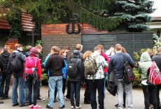 Słuchacze stoją przy tablicy pamiątkowej.