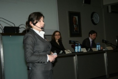 Pani stoi i przemawia, ma mikroport przy uchu