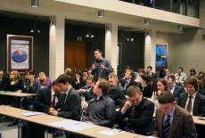 fot. Sebastian Szulfer/KSAP Zgromadzeni goście siedza w ławkach na auli, Pan stoi i mówi do mikrofonu