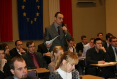 Uczestnik spotkania stoi i mówi do mikrofonu