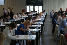 Sala egzaminacyjna, kandydaci siedzą przy stolikach i piszą egzamin