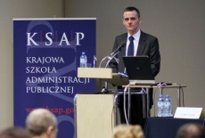 Pan Paweł Banaś stoi  przy mównicy i przemawia