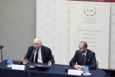 Józef Oleksy siedzi i mówi do mikrofonu obok niego siedzi pan