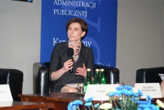 Prelegentka mówi do mikrofonu gestykulując. 