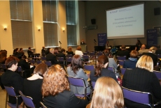 Widok na salę konferencyjną. Salę zapełniają uczestnicy, siedzą zwróceni w stronę rzutnika.