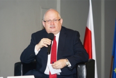 Dyrektor Jan Pastwa przemawia do mikrofonu. Za nim flaga Polski.